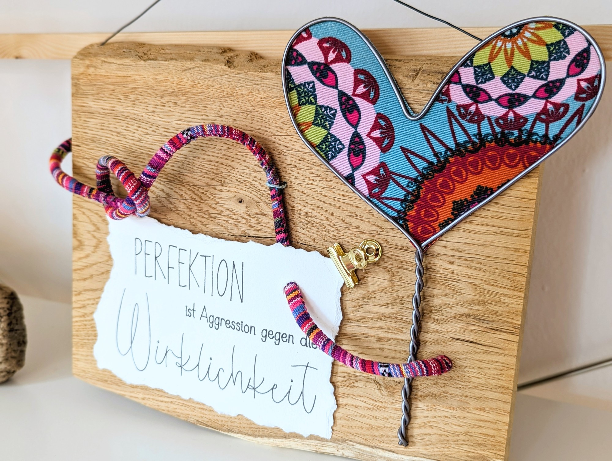 Dekoschild aus Holz mit buntem Stoffherz und Spruchkarte „Perfektion ist Aggression gegen die Wirklichkeit“